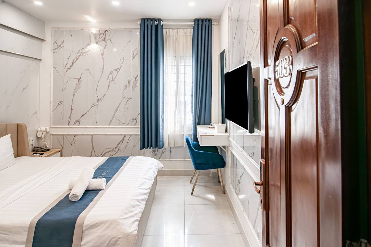 Une chambre d’hôtel avec un grand lit, un bureau, une télévision et une salle de bain avec douche et toilettes.