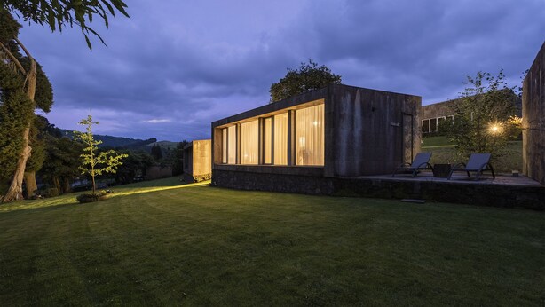 A modern house with large windows, a stone foundation, and a well-maintained lawn.