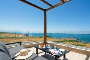 A balcony with a view of the sea, a table with a hat, a watermelon, and glasses. - Beachfront Villa w/Private Pool, Kids area and BBQ (Stavromenos)