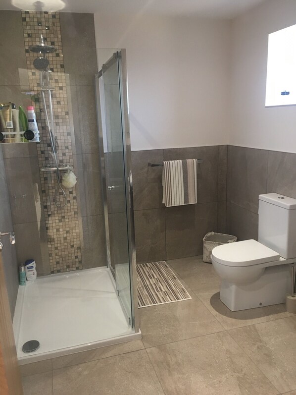 Un baño moderno con cabina de ducha de vidrio, inodoro y lavabo.