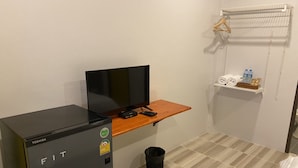 Une petite pièce comprenant un lit, un bureau avec un ordinateur et un réfrigérateur.