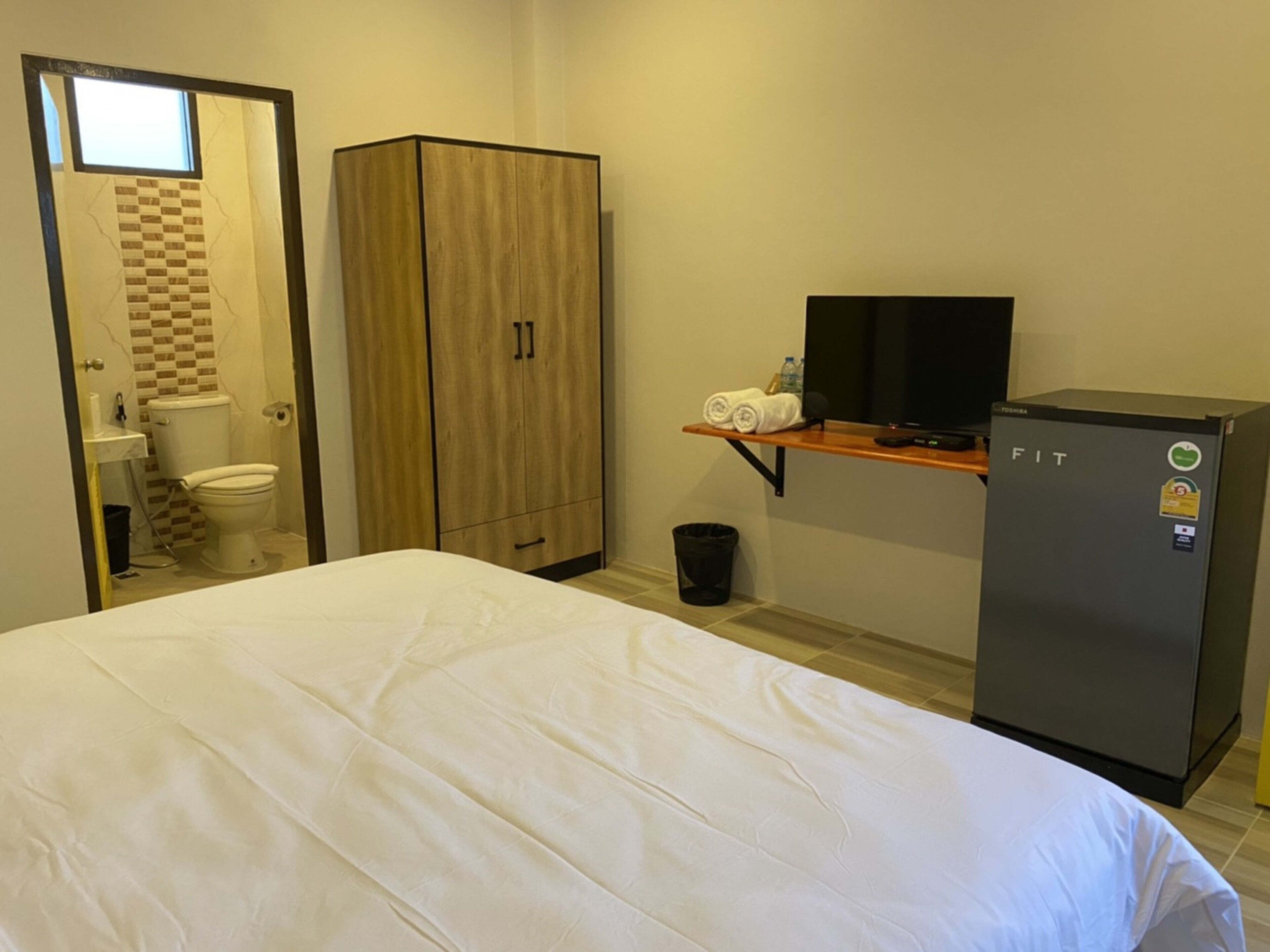 A hotel room with a bed, a wardrobe, a television, and a refrigerator.