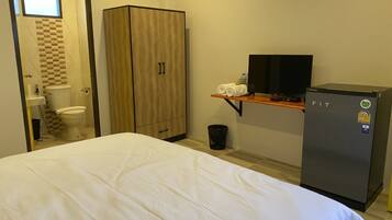 Una habitación de hotel con una cama, un armario, un televisor y un refrigerador.