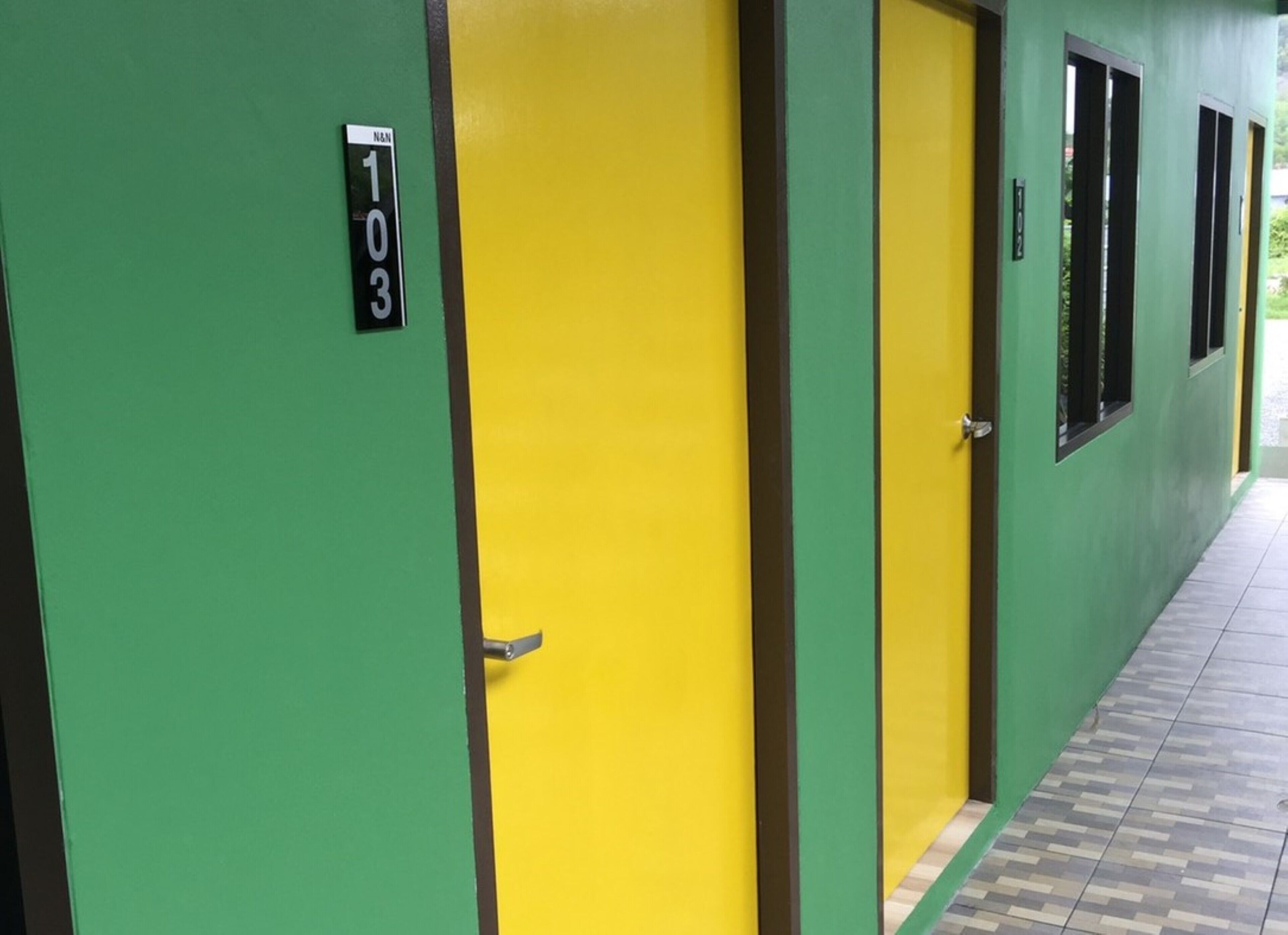A hallway with green and yellow doors, each marked with a number.