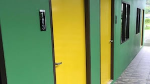 Un couloir aux murs verts et aux portes jaunes, chacune étant marquée d’un numéro.