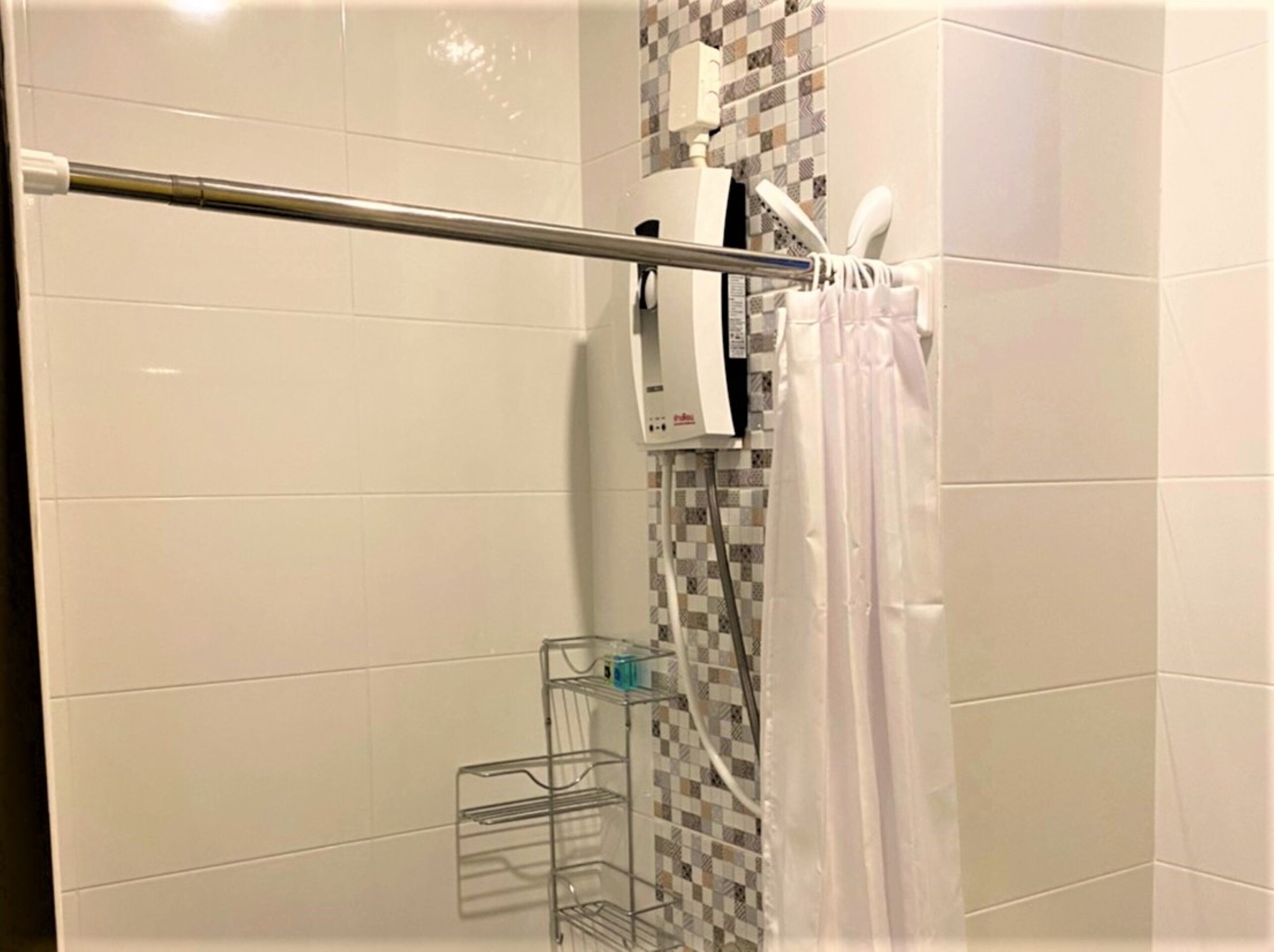 Un área de ducha con una barra de apoyo metálica, un toallero blanco y un cabezal de ducha.
