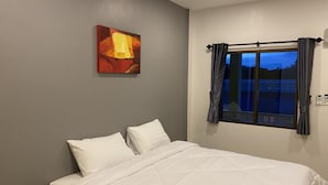 Une chambre à coucher avec un lit, un tableau accroché au mur et une fenêtre avec des rideaux.