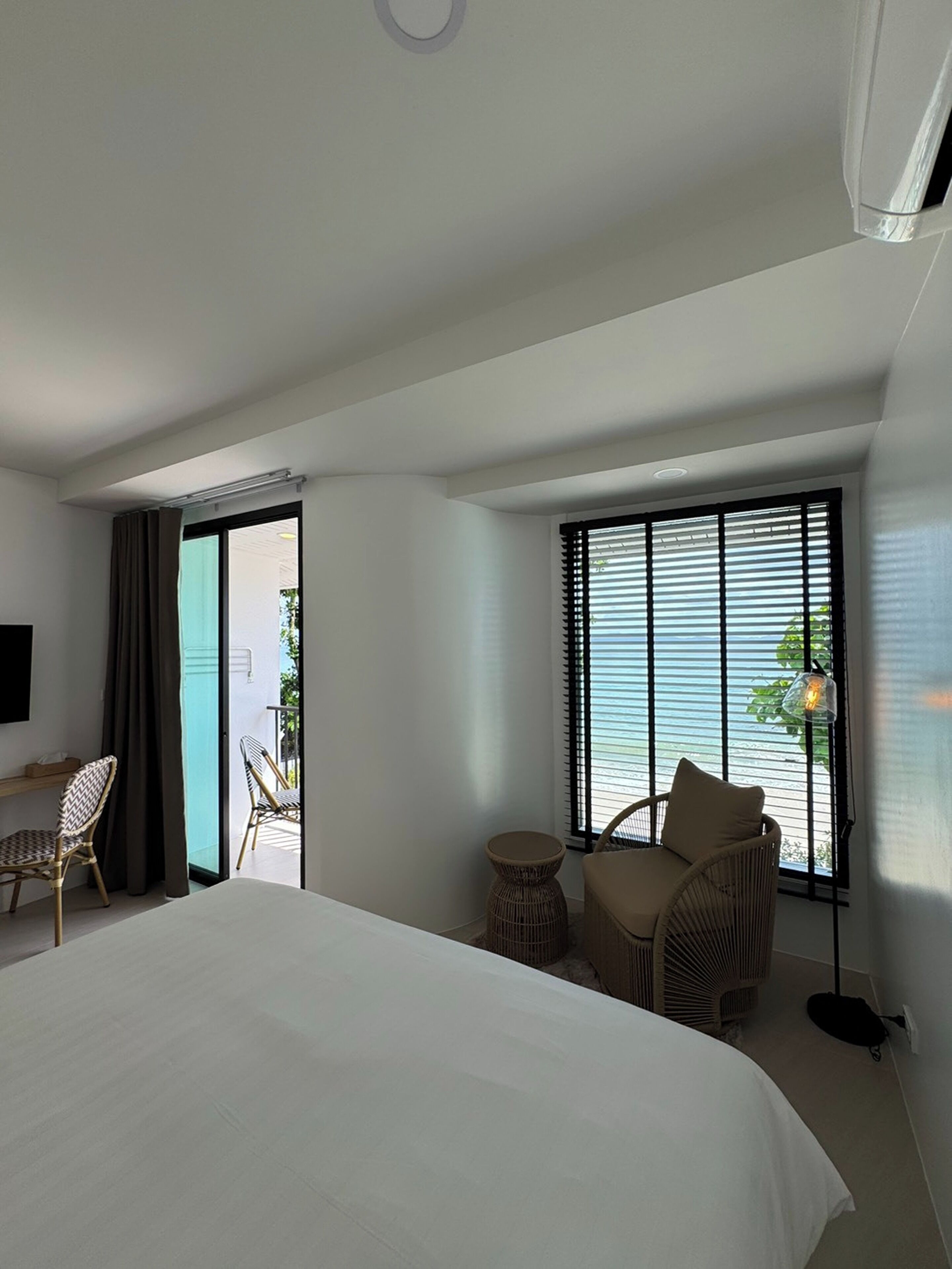 Habitación de hotel con una cama, una silla, una mesita y vistas al exterior a través de una ventana.