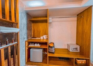 Une salle de bain compacte et bien aménagée, avec des étagères en bois, un petit réfrigérateur, des toilettes et un espace douche.