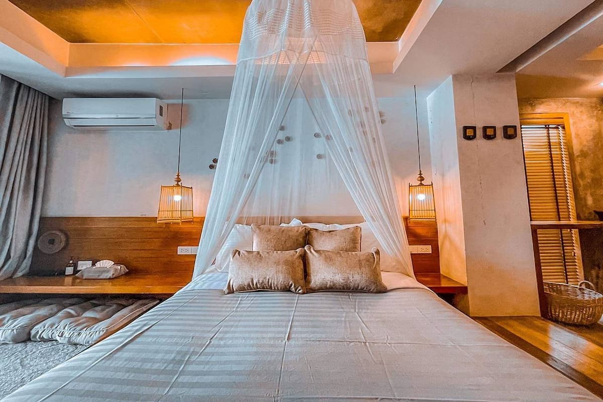 A bedroom with a canopy bed, bedside lamps, and a wooden headboard.