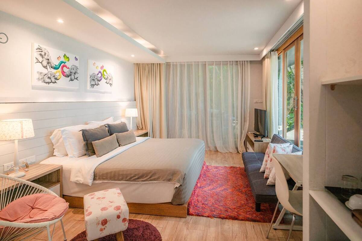 A modern bedroom with a large bed, bedside tables, a TV, and a desk with a chair.
