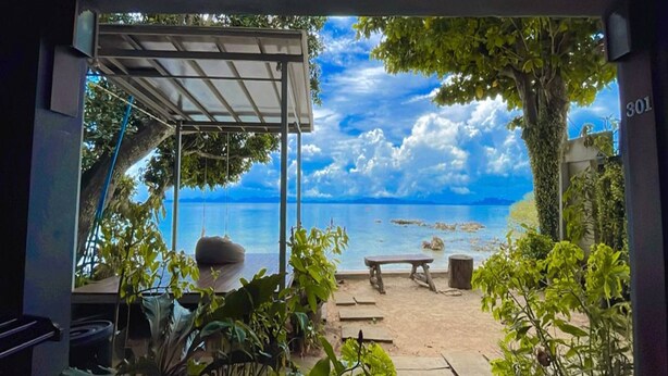 Un espacio al aire libre techado con una hamaca, un banco y vistas a la playa y al mar.