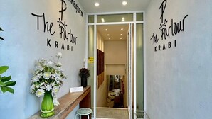 Un área de recepción con un mostrador, una silla, un florero y una puerta que da a una habitación.
