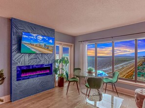 Una sala de estar moderna con un ventanal grande, un televisor de pantalla plana, una chimenea y un comedor.