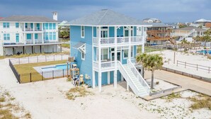 Een huis aan het strand met een twee verdiepingen, een balkon en een zwembad.
