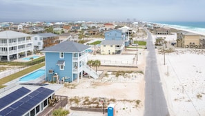 A beachfront property with a large blue building, a swimming pool, and a beach access road.