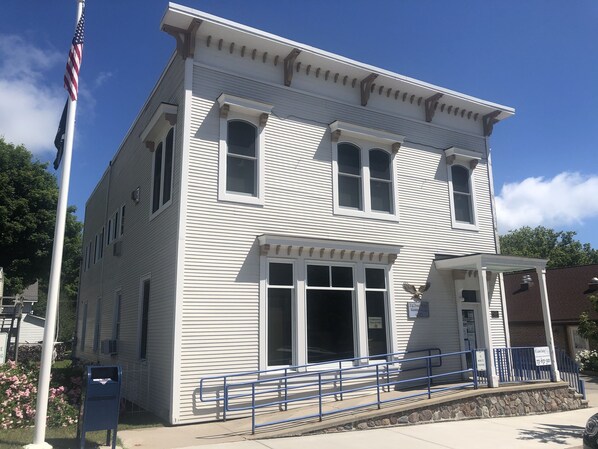 A two-story building with a white exterior, large windows, and a covered porch area.