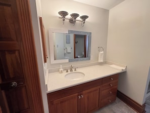 A bathroom with a wooden vanity, a large mirror, and a sink.