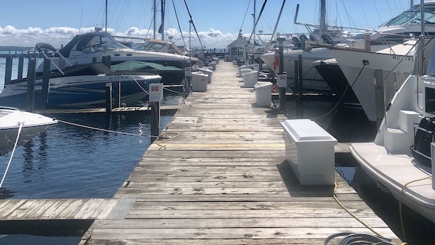 Uma marina com barcos atracados ao longo de um cais de madeira.