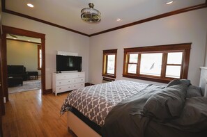 A bedroom with a bed, a dresser, a television, and two windows.