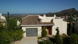 A Mediterranean-style building with a tiled roof, a garage, and a view of a coastal landscape. - La Manga Club Monte Verde Villa 352 (La Manga Club, Cartagena)