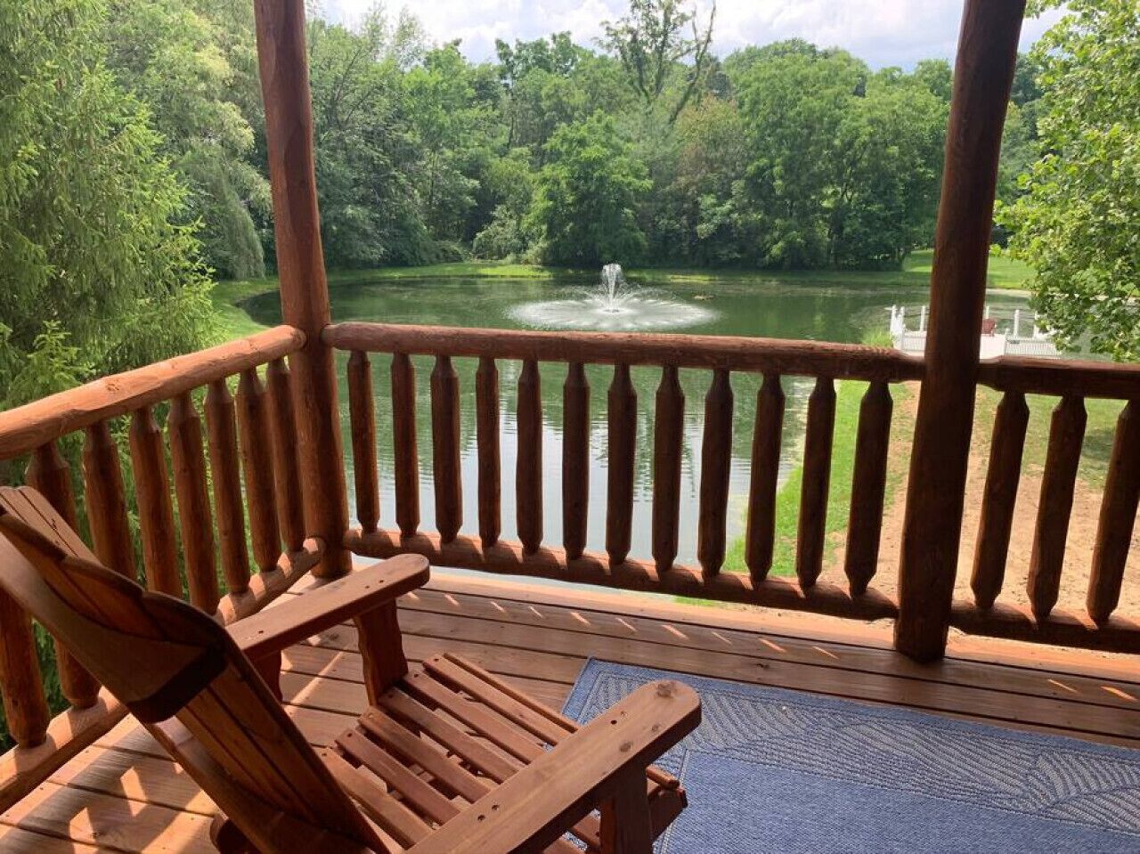 A wooden deck with a view of a lake and a fountain.
