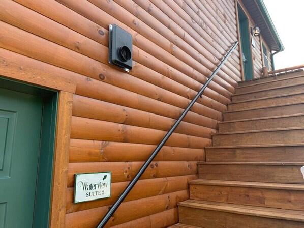 A wooden staircase leading to a door with a sign reading "Waterview Suite 2".