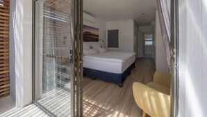 Ein Schlafzimmer mit Bett, Stuhl und einer Glastür zum Balkon.