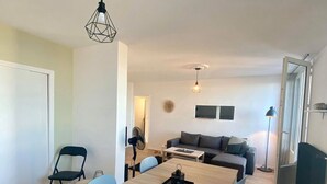 A modern living room with a wooden dining table, a sofa, and a TV. - T3 sea view apartment (Bastia)