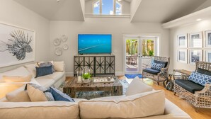 A spacious living room with a large TV, comfortable seating, and a view of the outdoors. - SOUTHERN CROSS ~ Conveniently Located 3 Bedroom, 2.5 Bathroom Gem w/ Pool (Key West)