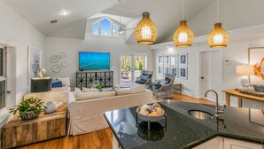 A modern kitchen with a black countertop, a sink, and a dining area with a table and chairs. - SOUTHERN CROSS ~ Conveniently Located 3 Bedroom, 2.5 Bathroom Gem w/ Pool (Key West)