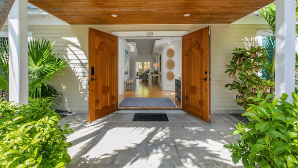 A wooden door with a number 1219 above it, leading to an interior space with a dining area and a kitchen visible through the doorway. - SOUTHERN CROSS ~ Conveniently Located 3 Bedroom, 2.5 Bathroom Gem w/ Pool (Key West)