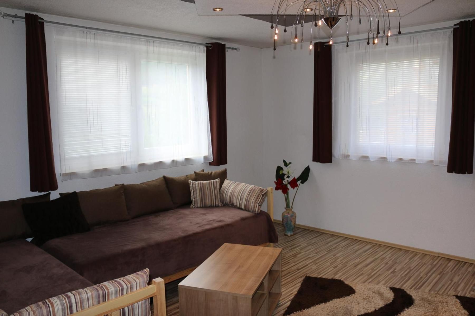 A living room with a sofa, a coffee table, and a decorative vase with flowers.