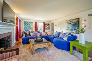 A living room with a fireplace, blue sofa, wooden coffee table, and a green side table.