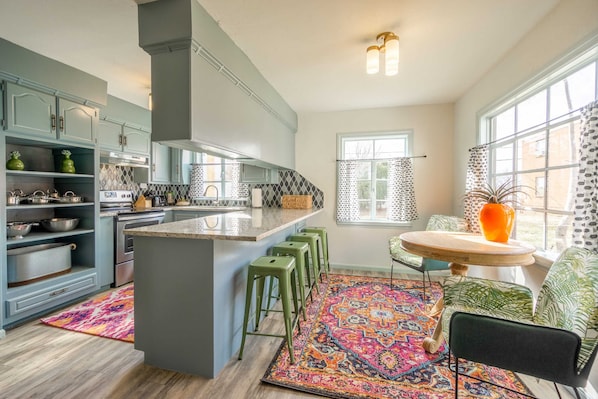 A modern kitchen with a central island, bar stools, and a dining area with a round table and chairs.