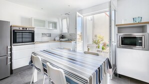 Una cocina moderna con una amplia mesa de comedor, electrodomésticos integrados y vistas al exterior.