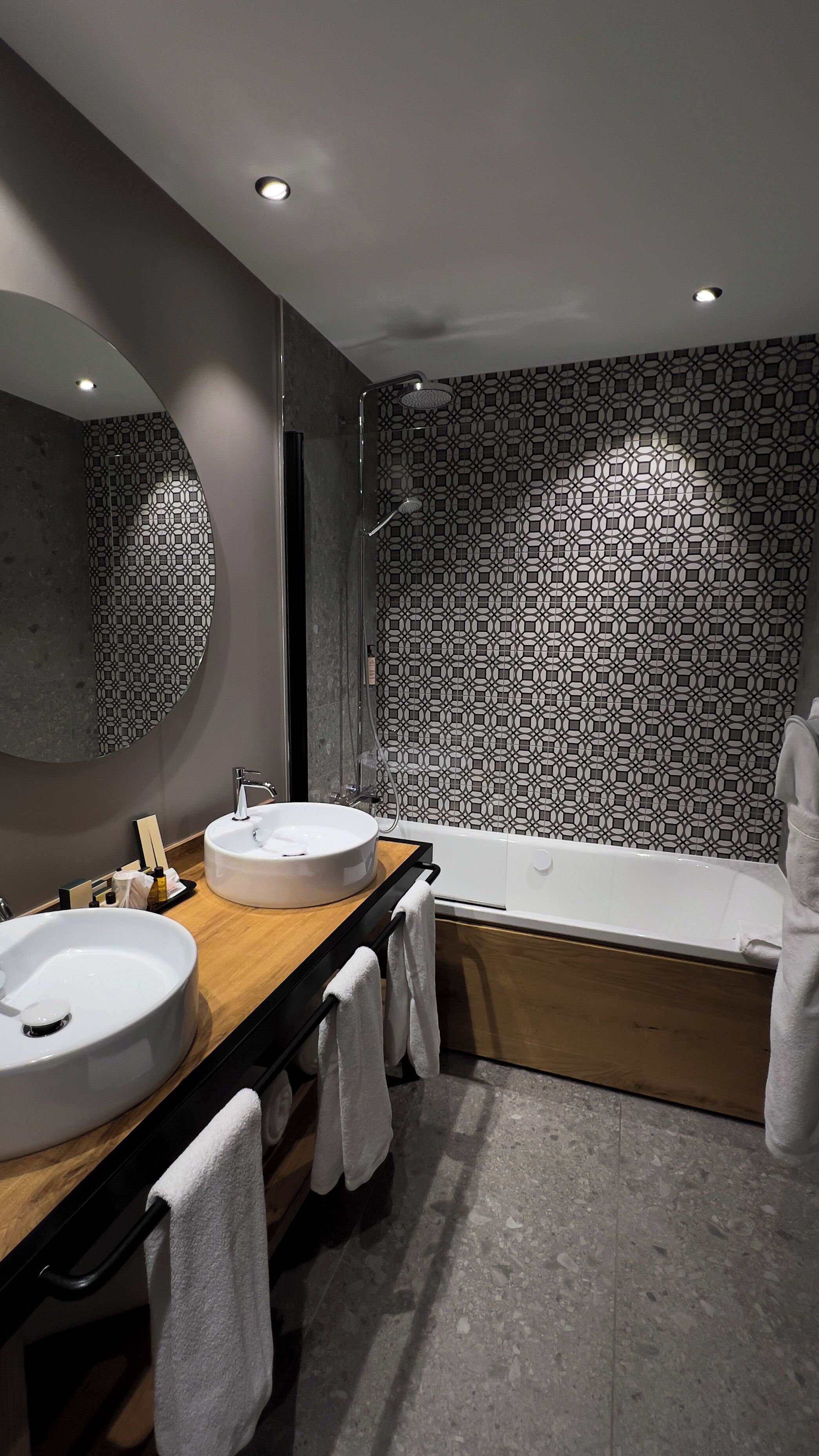 A modern bathroom with two sinks, a large mirror, and a bathtub.