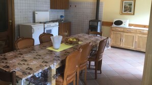 Cozinha compacta com mesa, cadeiras, geladeira, fogão e micro-ondas.