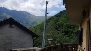 Um caminho de pedra leva a um edifício com cerca de madeira e montanhas ao fundo.