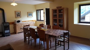 Uma área de refeições com mesa, cadeiras, um armário e um fogão.
