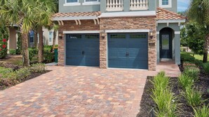 A two-story house with a balcony, two garages, and a paved driveway. - Private Pool, Game Room & Waterpark Access – 141LA (Reunion)