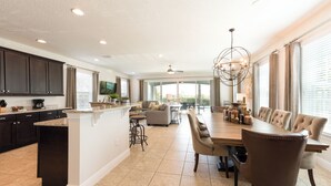 A spacious kitchen with dark cabinets, a central island, and a dining area with a large table and chairs. - Private Pool, Game Room & Waterpark Access – 141LA (Reunion)