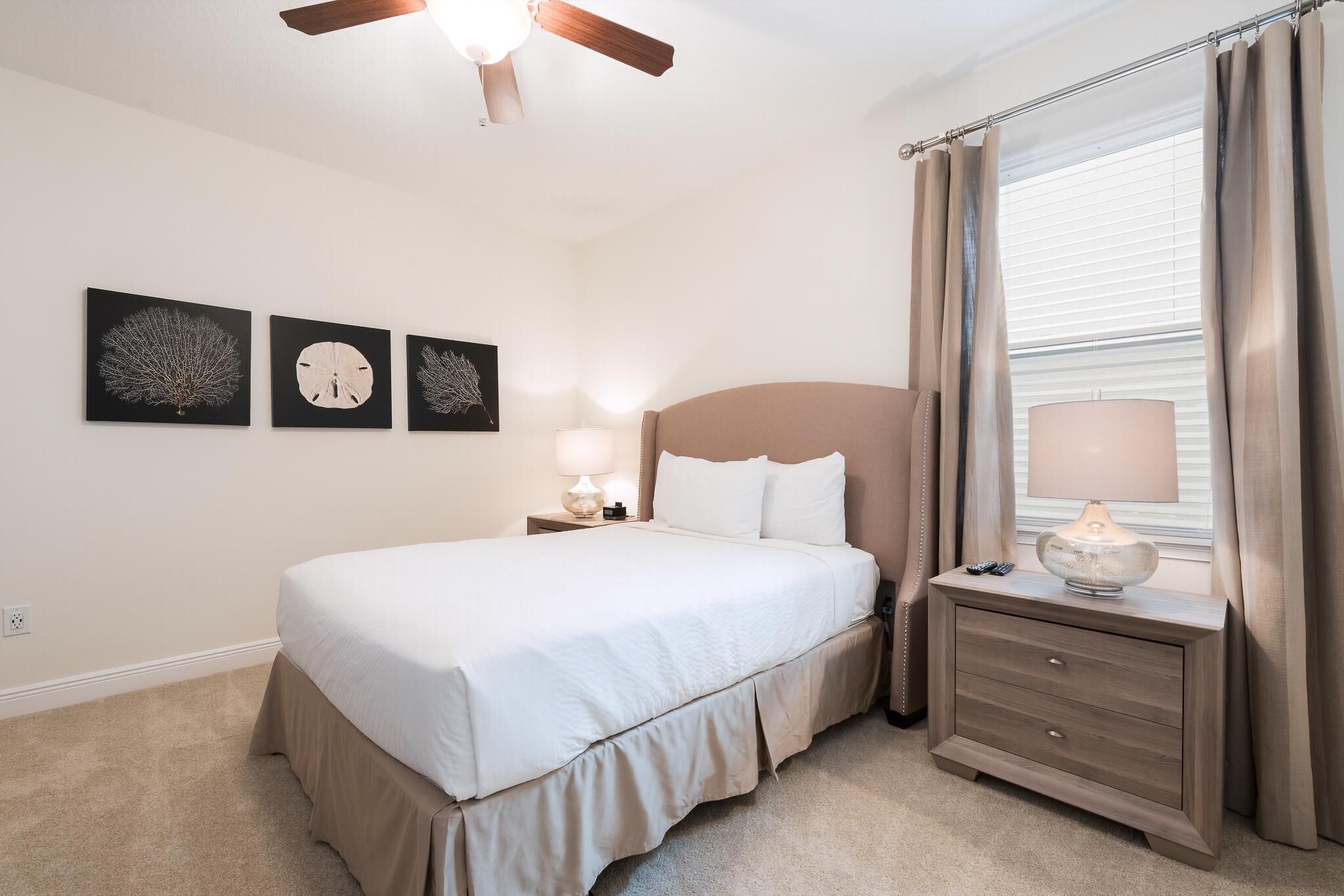 A bedroom with a bed, bedside table, lamp, and three wall art pieces.