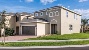 A modern two-story house with a garage, a well-maintained lawn, and a clear sky.