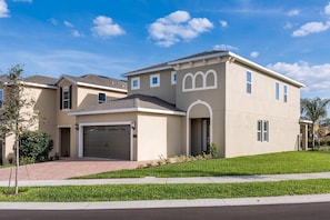 A modern two-story house with a garage, a well-maintained lawn, and a clear sky.