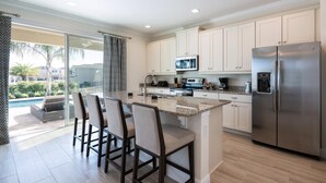 A modern kitchen with a large island, stainless steel appliances, and a view of a swimming pool.