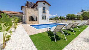 A modern house with a swimming pool, outdoor seating, and a stone archway.