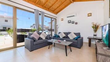 A modern living room with a grey sofa set, a coffee table, and a TV on a wooden cabinet.