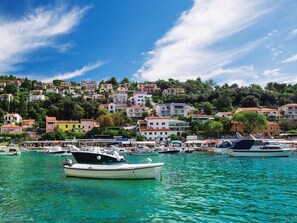 A coastal town with boats docked in the marina, colorful buildings, and a clear blue sky. - Family-friendly apartment with terrace and wonderful sea view (Rabac)