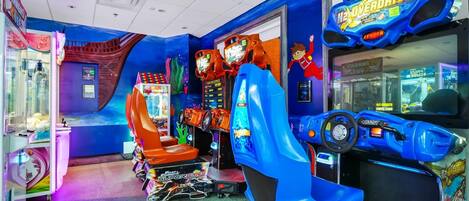 An indoor arcade with various gaming machines, including a blue racing game and a claw machine.